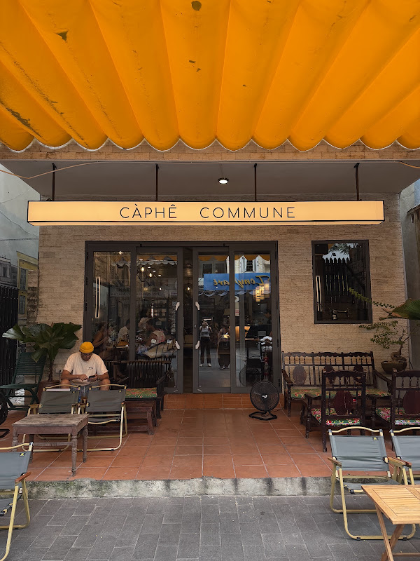 Front entrance of Càphê Commune under its bright yellow awning