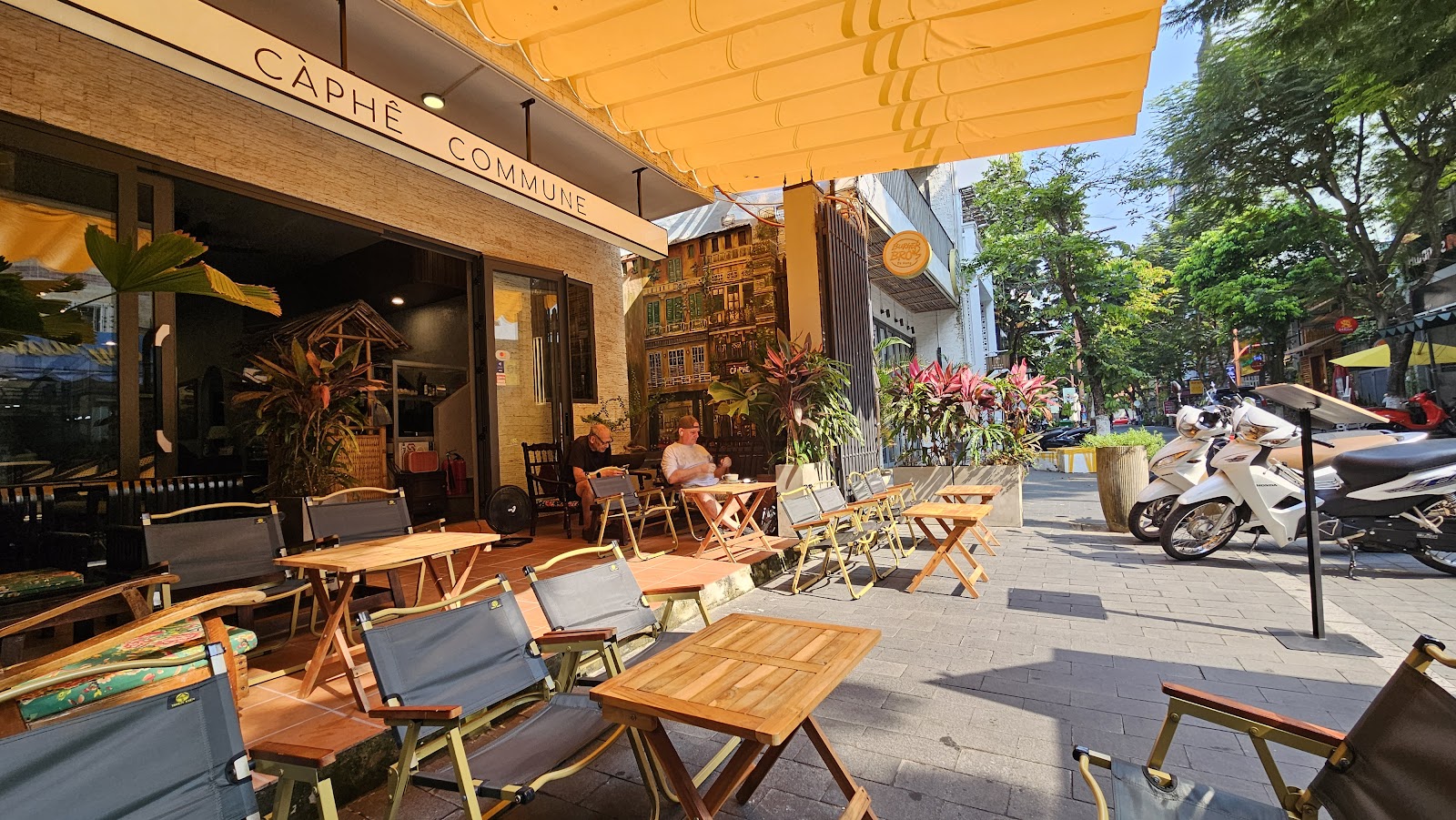 Càphê Commune beneath its yellow awning, with outdoor café tables